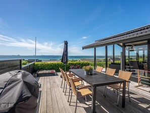 A wooden deck with outdoor furniture, a grill, and a view of the sea. - "Gertina" - 100m from the sea by Interhome (Knebel)