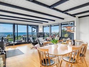 A spacious room with a large dining table, comfortable seating, and a view of the sea. - "Gertina" - 100m from the sea by Interhome (Knebel)