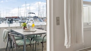 Un balcón con una mesa, sillas y vistas a un puerto deportivo con barcos.