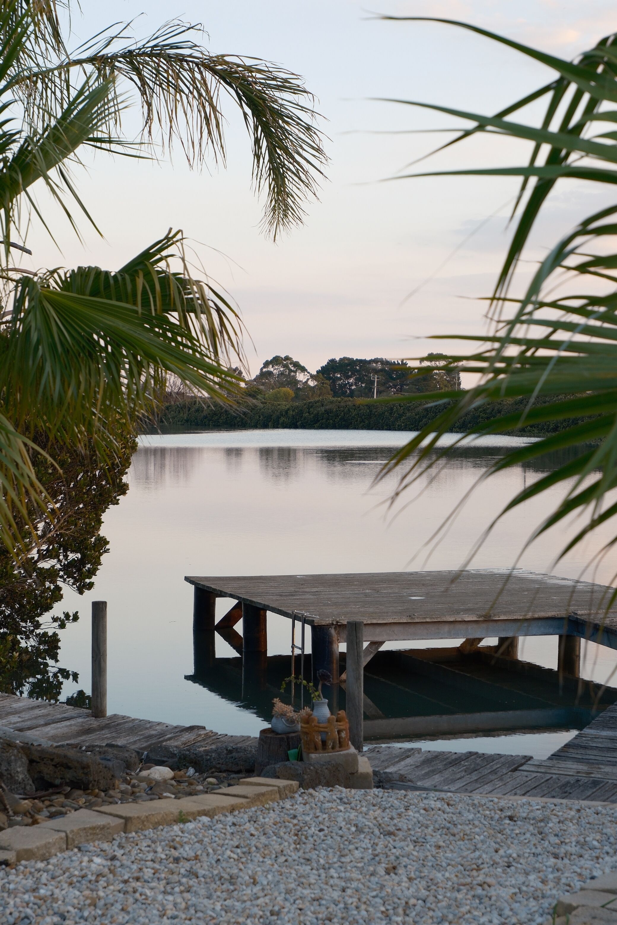 A calm lake with a wooden dock and a small structure at the end.