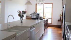 A kitchen with a large island, pendant lights, and a view to the outdoors. - Waterfront retreat w/private dock, kayaks & animal encounters (Tooradin)