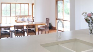 A kitchen with a white countertop, a sink, a chandelier, and a dining area with wooden furniture. - Waterfront retreat w/private dock, kayaks & animal encounters (Tooradin)