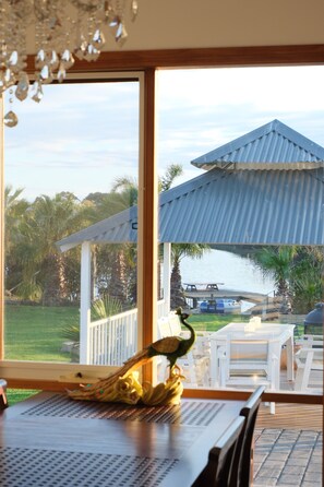 Un comedor con vista a una masa de agua, mobiliario exterior y una estructura de pérgola.