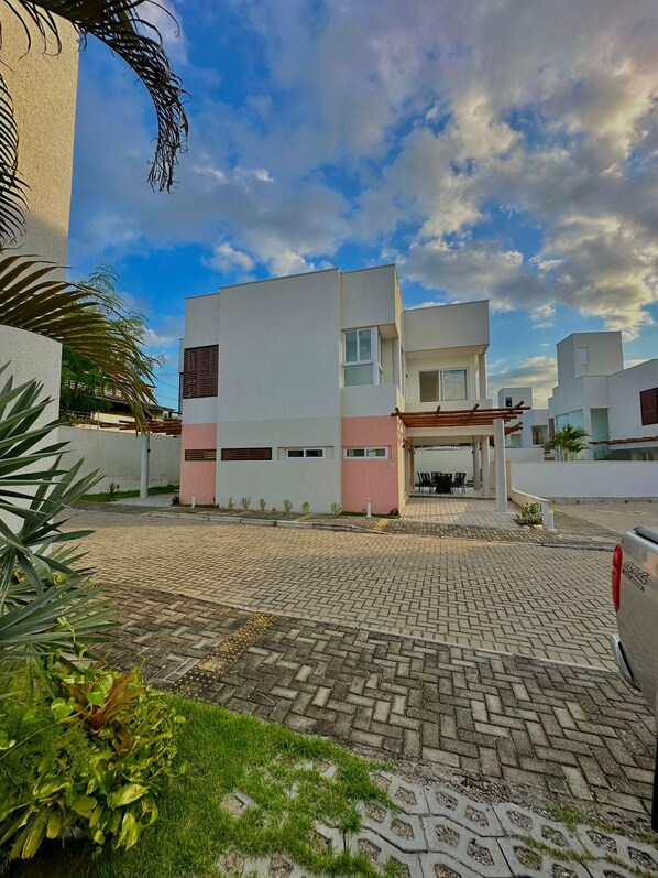 A modern building with a flat roof, a covered outdoor seating area, and a paved driveway.