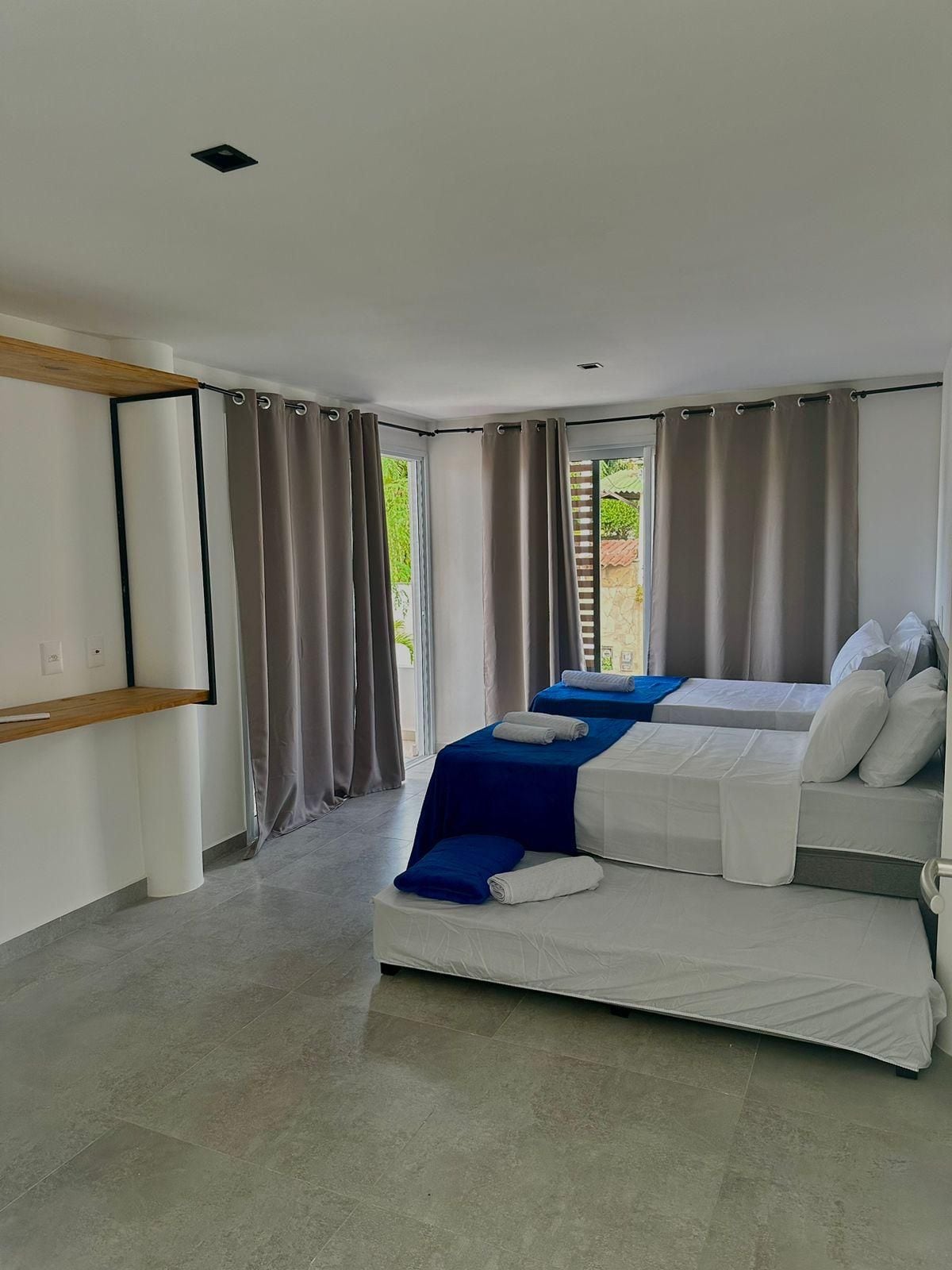 Une chambre d’hôtel moderne avec un grand lit, une étagère en bois et une vue sur la verdure.