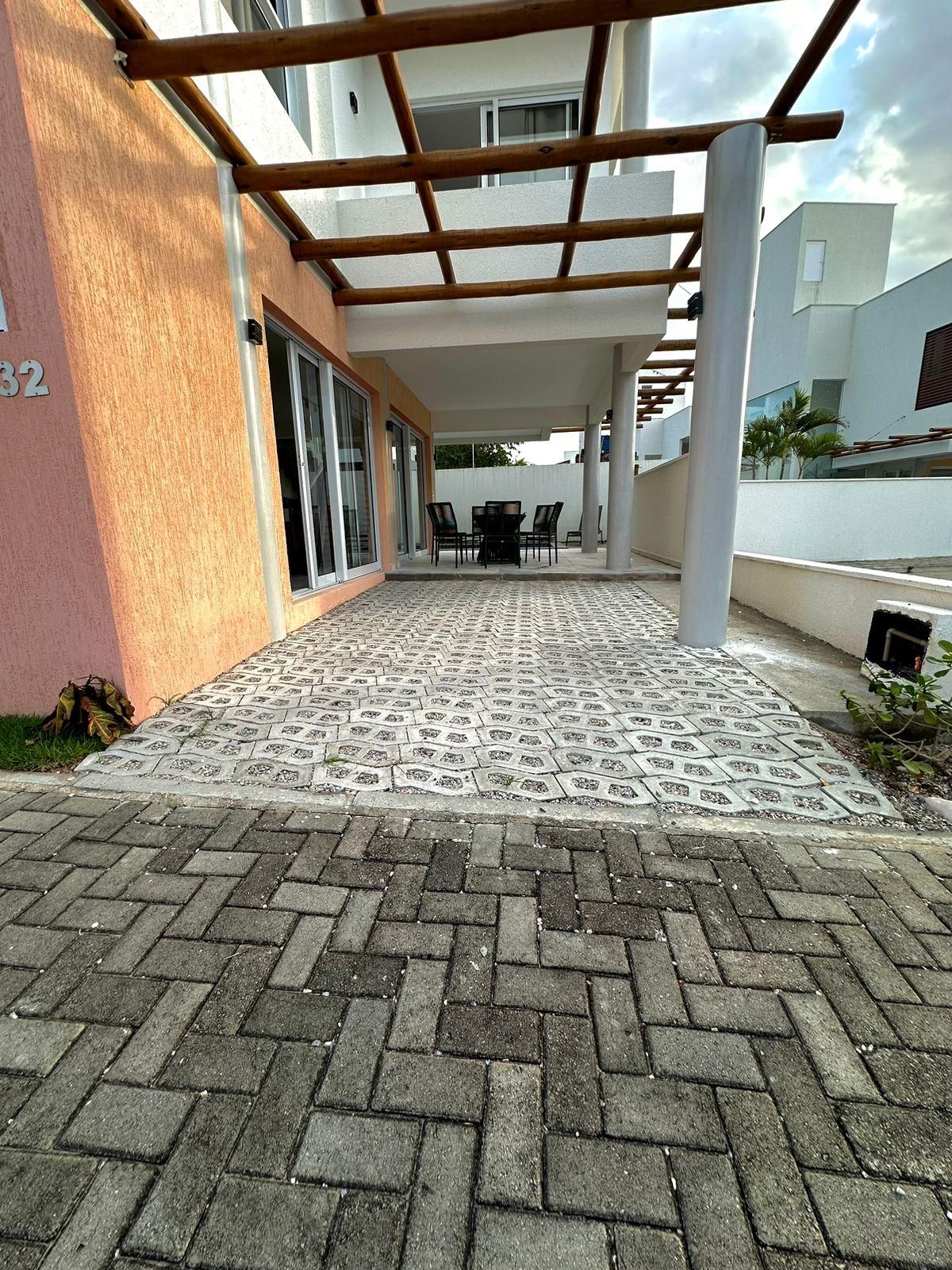 Área externa coberta com um pátio de tijolos, pérgola e um conjunto de assentos.