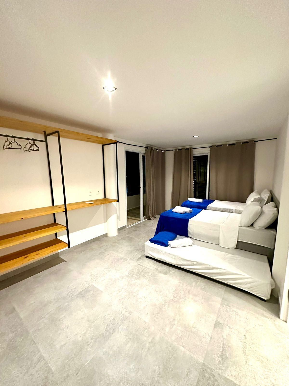 Quarto moderno com cama, um banco de madeira e um guarda-roupa.