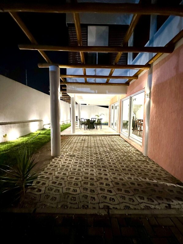 An outdoor patio area with a patterned floor, a pergola, and a seating arrangement.