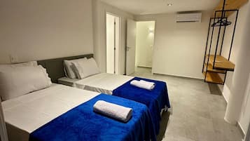 Habitación de hotel con dos camas, un armario y un baño visible a través de una puerta abierta.