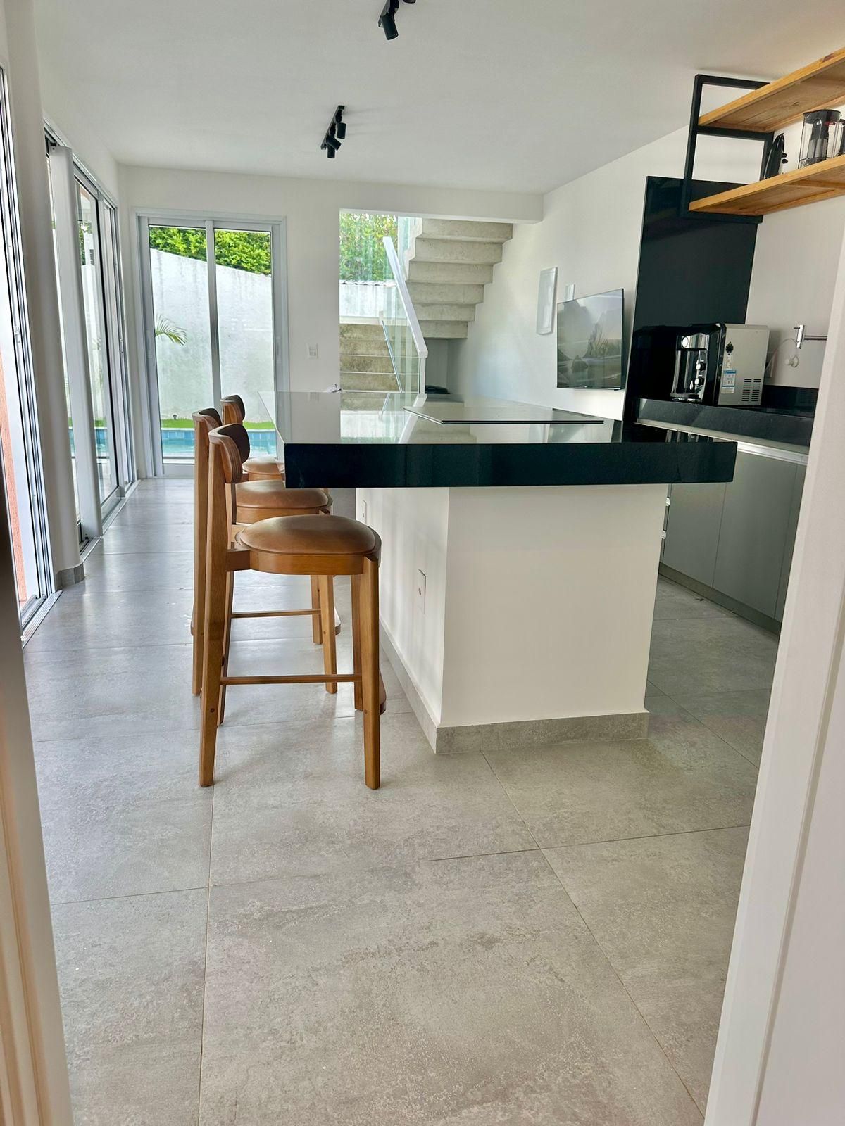A modern kitchen with a central island, bar stools, and a staircase leading to an outdoor area.