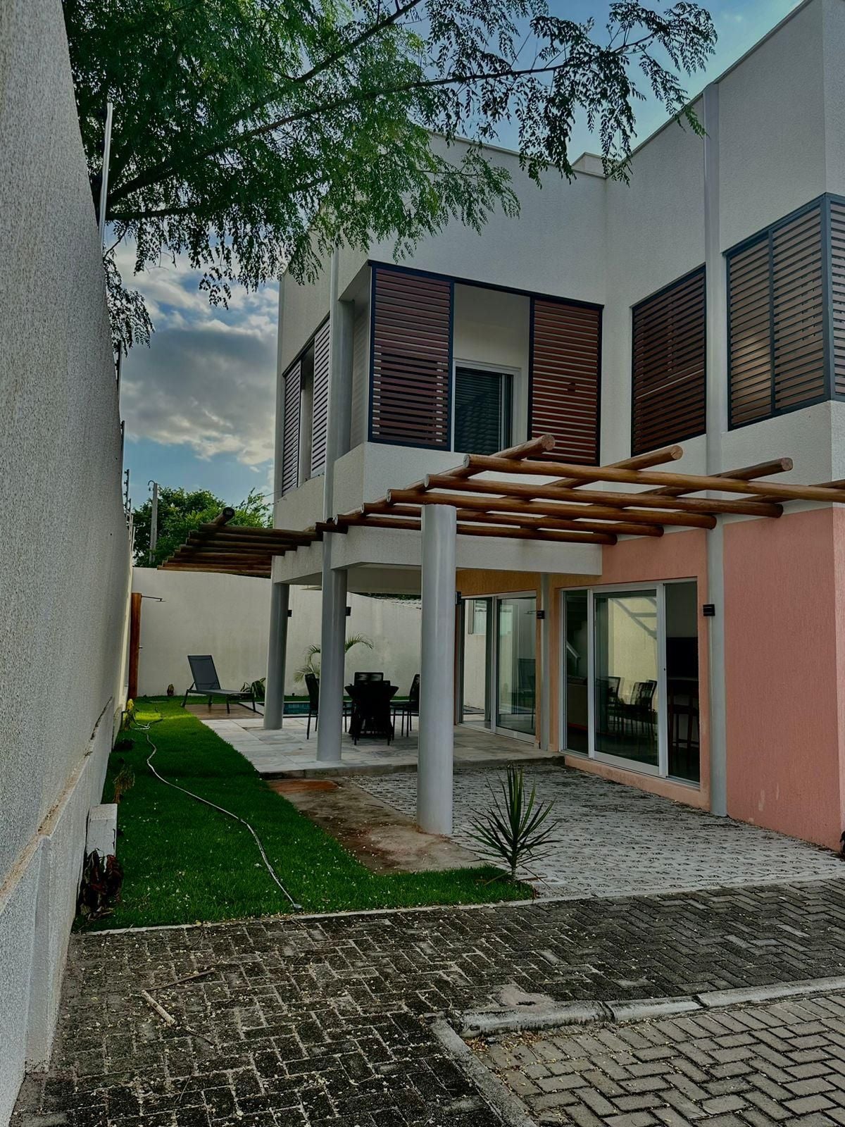 A modern building with a covered patio area, outdoor seating, and a well-maintained lawn.