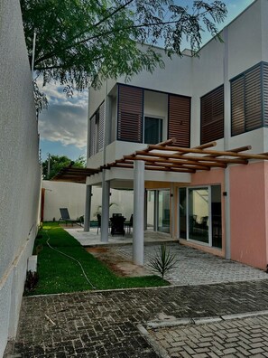 A modern building with a covered patio area, outdoor seating, and a well-maintained lawn. - Praia da Pipa - Mar e Descanso (Tibau do Sul)