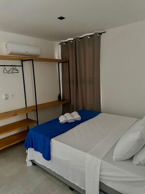A single-bed room with a bunk bed, a blue bedspread, white pillows, and a brown curtain.