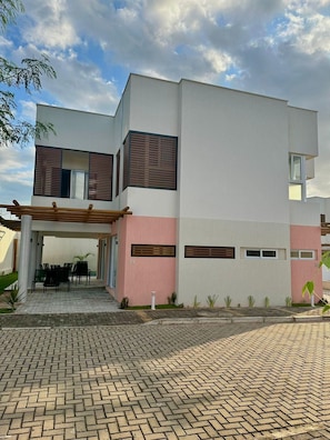 Una casa moderna de dos pisos con un porche cubierto y un camino de entrada pavimentado.