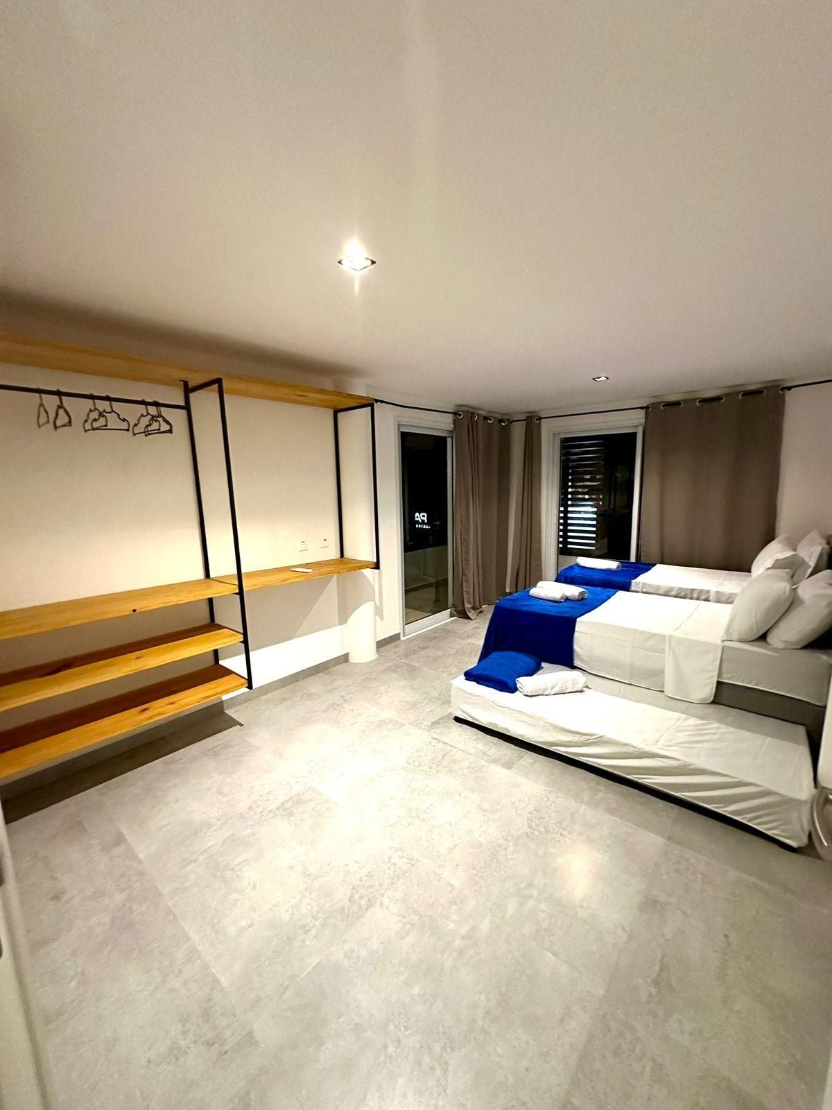 Un dormitorio moderno con una cama, un banco y una estantería de pared.