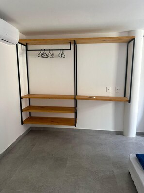 A room with a built-in shelving unit with three wooden shelves and a hanging rack.