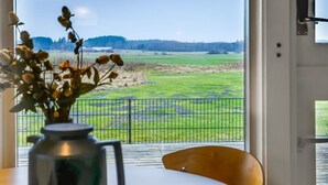Ein Zimmer mit einem großen Fenster, einem Metallgeländer und Blick auf ein grünes Feld.