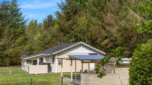 A single-story mobile home with a covered patio, surrounded by a fenced yard and dense forest. - "Ansfried" - 900m from the sea by Interhome (Sæby)