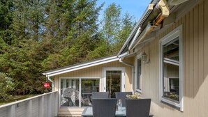 A covered outdoor patio with a table and chairs, a flag, and a view of a forested area. - "Ansfried" - 900m from the sea by Interhome (Sæby)