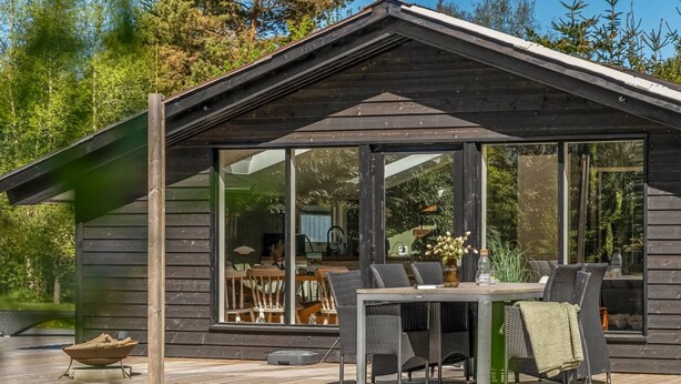 A wooden cabin with a deck, outdoor seating, and a large window. - "Bedrija" -  from the sea by Interhome (Hals)