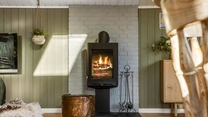 A room with a fireplace, a wooden bench, a hanging plant, and a rustic metal container. - "Bedrija" -  from the sea by Interhome (Hals)