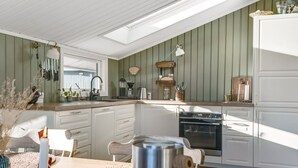 A modern kitchen with a skylight, white cabinets, and a built-in oven. - "Bedrija" -  from the sea by Interhome (Hals)