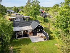 A single-story building with a covered patio area, surrounded by lush greenery and other residential structures. - "Nikica" -  from the sea by Interhome (Hadsund)