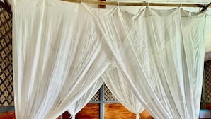 Un lit à baldaquin, avec des oreillers et un coussin décoratif.
