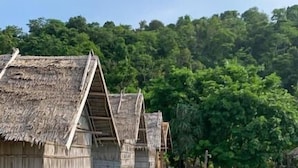 Des bungalows sur pilotis avec toits de chaume, des passerelles en bois et une eau turquoise cristalline.