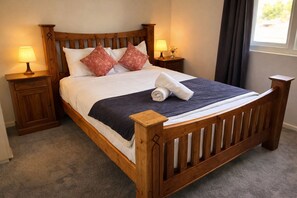 A wooden four-poster bed with a dark blue bedspread, two decorative pillows, a rolled white towel, and two bedside lamps. - Cozy 1-bedroom apartment in amazing Kurraba Point (Kurraba Point)