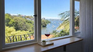 Ein Fenster mit Blick auf einen Fluss, Boote und viel Grün.
