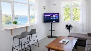 Ein modernes Wohnzimmer mit Fernseher, zwei Sesseln, einem Tisch und einer Couch.