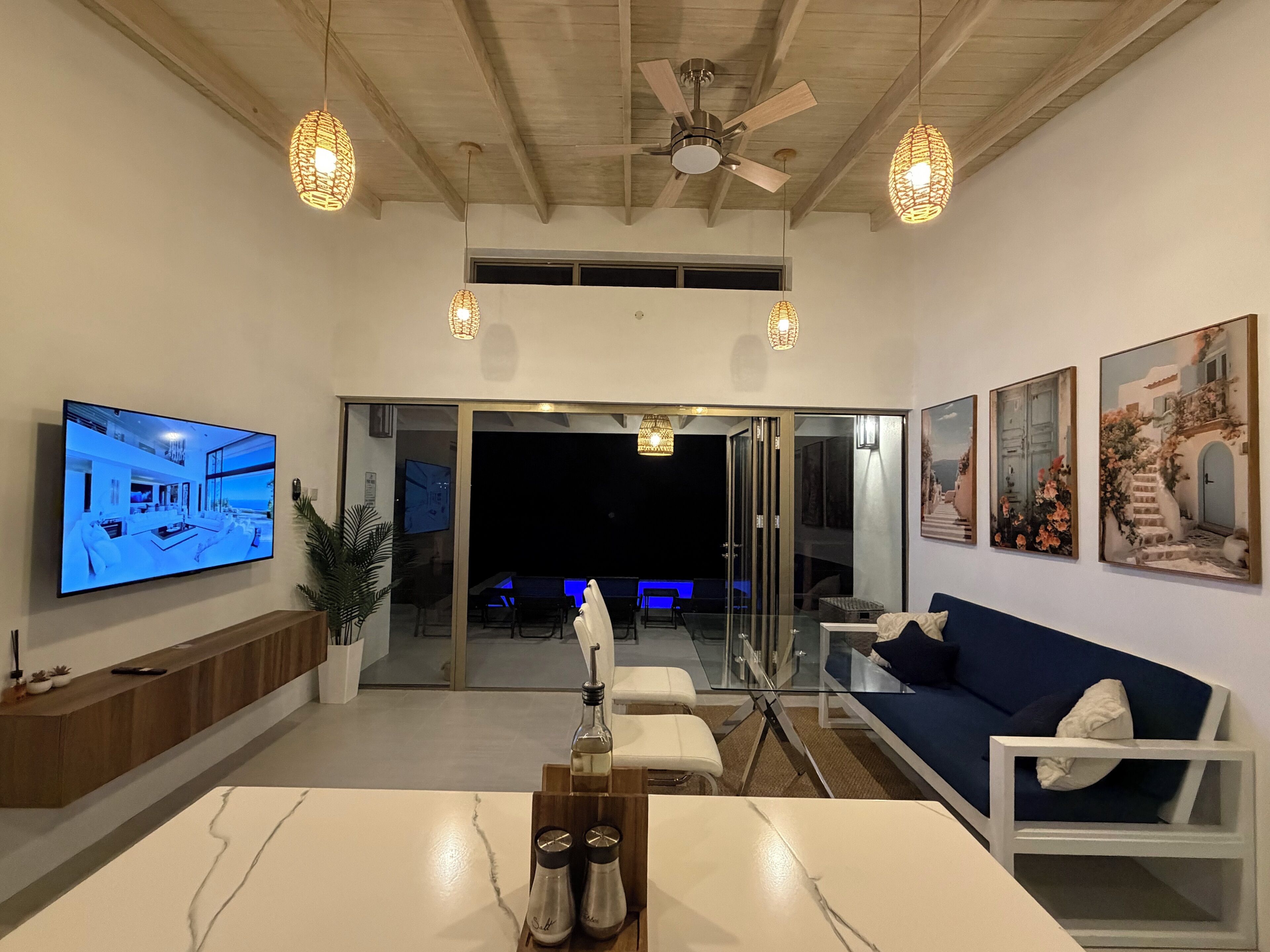Una sala de estar moderna con un televisor de pantalla plana, una mesa de comedor con salerosos y pimenteros, y un sofá.