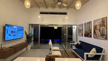 Una sala de estar moderna con un televisor de pantalla plana, una mesa de comedor con salerosos y pimenteros, y un sofá.