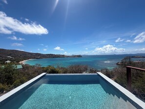 On voit clairement une piscine, avec en arrière-plan un paysage côtier et des collines lointaines.