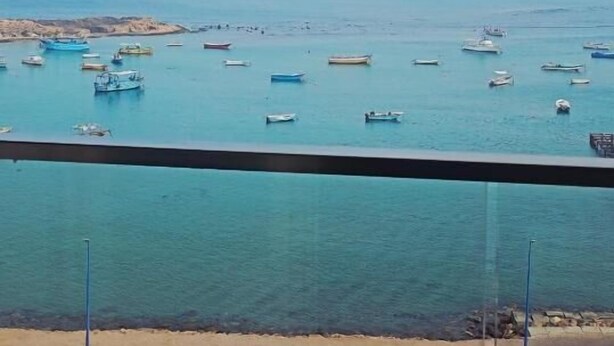 Vista costera con barcos y una playa de arena.