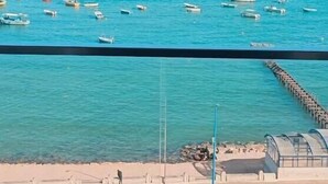 Vista costera con barcos en el agua, un muelle y una playa de arena.