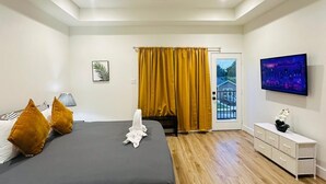 Een slaapkamer met een bed, een plafondventilator, een televisie, een raam met gordijnen en uitzicht.