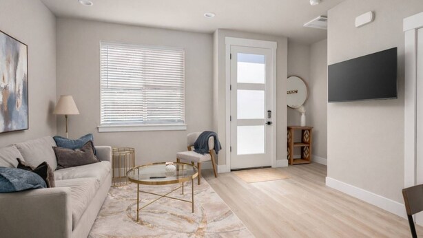 A living room with a sofa, coffee table, and a television mounted on the wall. - Chiquita Bonita | Brand New, Stylish & Spotless, Pet Friendly, Walk to Park, Minutes from Downtown (Tigard)