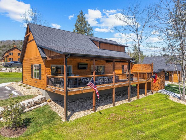 Une cabane en bois dotée d’un balcon, d’un drapeau et de fondations en pierre.