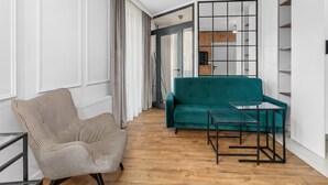Ett modernt vardagsrum med en turkos soffa, en fåtölj i hundtandsmönster och ett soffbord i glas.