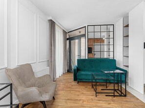 Un salon moderne avec un canapé de couleur turquoise, un fauteuil à motif pied-de-poule et une table basse en verre.