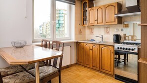 A kitchen with wooden cabinets, a gas stove, a sink, and a dining table with chairs.