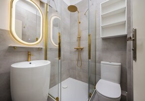 Ein modernes Badezimmer mit einem Standwaschbecken, einer Toilette und einer gläsernen Duschkabine.