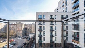 Eine moderne Wohnung mit Balkon, großen Fenstern und Blick auf die Straße.