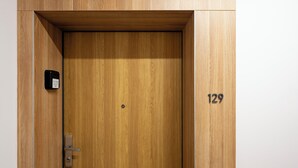 Eine Holztür mit einer numerischen Tastatur, einem Klingelknopf und einem kleinen Schild mit der Nummer 129.