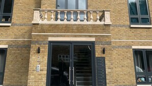 Un immeuble à plusieurs étages, doté d’une façade en briques, de grandes fenêtres et d’une entrée centrale avec une porte en verre.