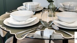 Une table à manger dressée avec des bols, des assiettes et des couverts blancs, ainsi qu  ’un verre transparent.