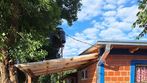 A fenced area with a brick building, a wooden pergola, and a tree.