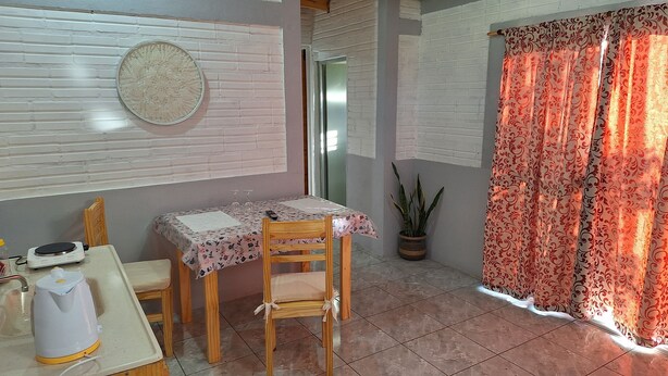 A dining area with a table, chairs, a kettle, and a potted plant.